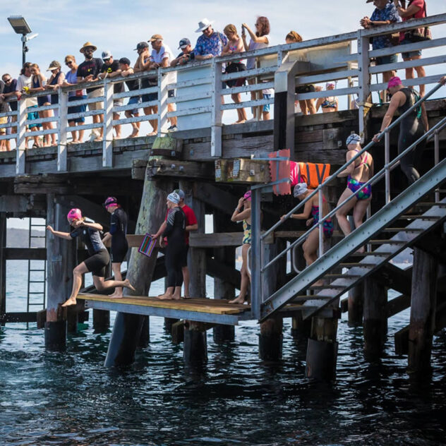 Participants at the previous Tathra Wharf to Waves event, ready to dive into the ocean for the race.
