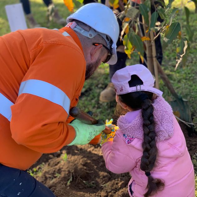 A child and Diona worker planting a tree together at Cecil Hills Early Education Centre.