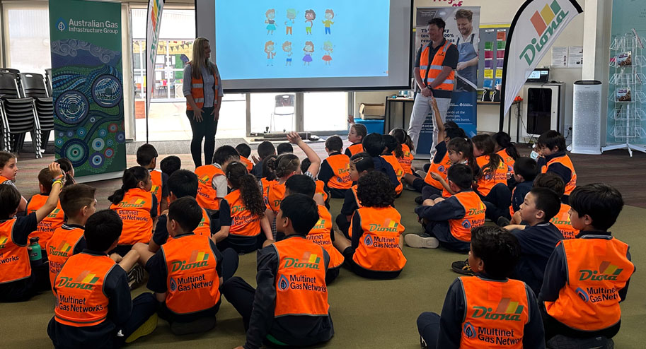 Children from McKinnon Primary School sitting attentively on the floor, listening to a presentation about renewable energy and safety during Digger Day.