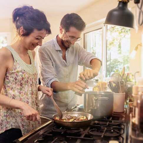 A couple cooking together on a gas stove top, showcasing the integral role of gas infrastructure in supporting daily life and community well-being.