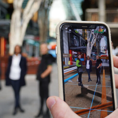 Close-up of a smartphone displaying an augmented reality app, visualising underground pipes beneath Queen St Mall in Brisbane, showcasing innovation in action.