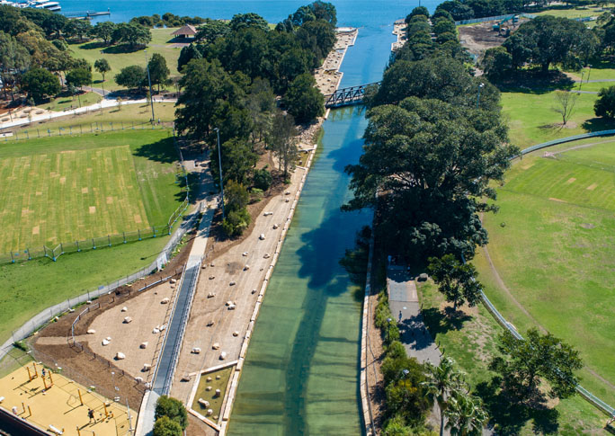 Johnstons Creek revitalised with natural sandstone, native plantings, and intertidal rock pools, showcasing enhanced ecological and social value.