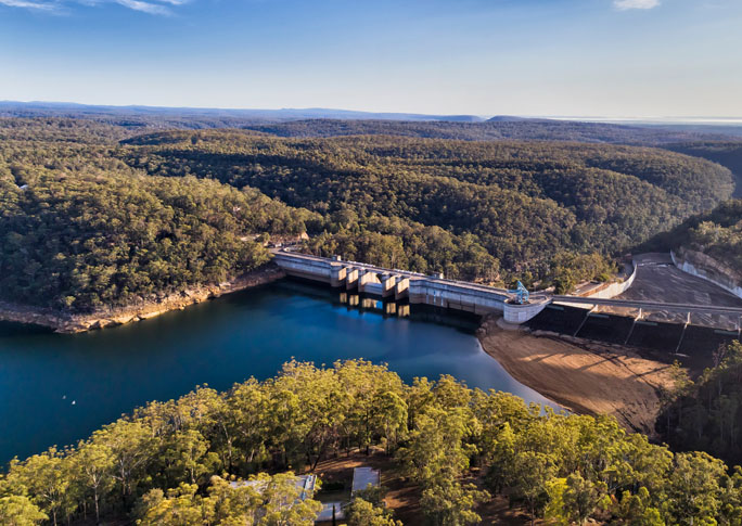 Aerial view of Warragamba Dam in NSW, surrounded by lush greenery.