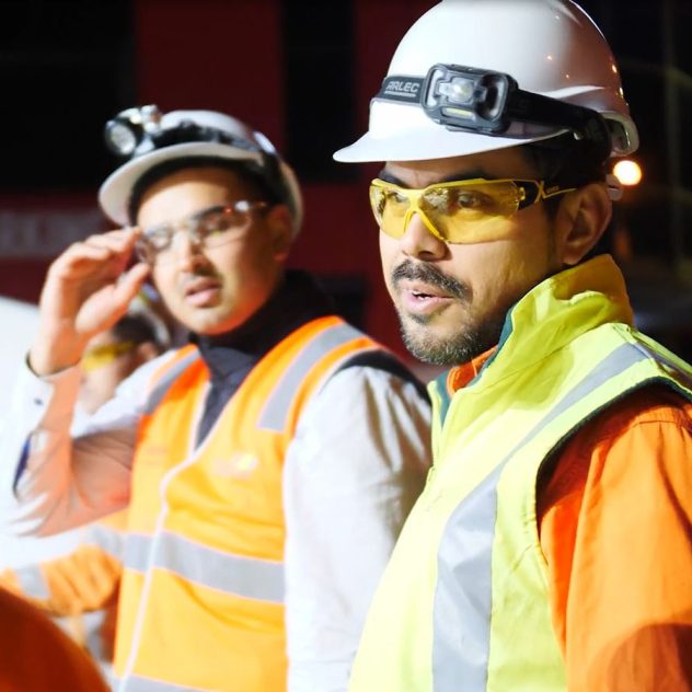 Two workers in high-visibility gear working diligently during the night shift on the Water North Zones program, actively engaged in upgrading water infrastructure.